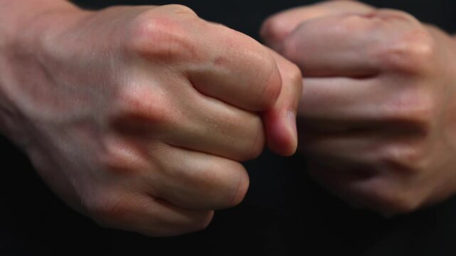 The man clenched his fists in anger and prepares for self-defense.
A man clenches his fists before a fight.
Anger and hatred.
A fighter clenches his fists before a fist fight