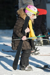 Young skier prepares for a day of winter fun on the snow-covered slopes surrounded by fellow...