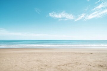 Fototapeta premium Expansive beach scene with soft sand, gentle waves, and a bright blue sky adorned with delicate wispy clouds