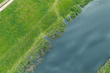 aerial top view of the small river flowing along coast, covered with a grass and canes.