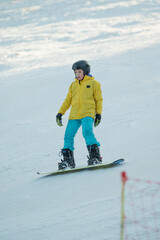 Snowboarder gracefully navigating a winter slope in a vibrant yellow jacket under clear blue skies...