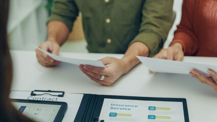 Close-up of Asian couple checking insurance documents and financial contract during advisor...