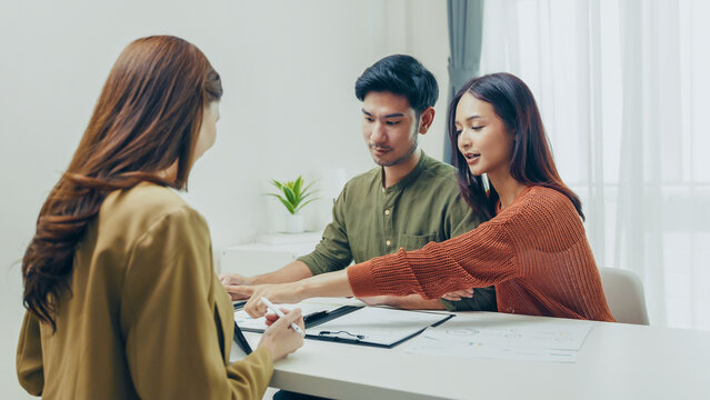 Young Asian couple discussing financial investment and insurance planning with professional advisor at modern office table. Real people, trust and finance concept.