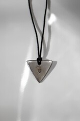 Stylish Silver Triangle Handmade Pendant on Black Cord on White Background. Modern Jewelry Accessory