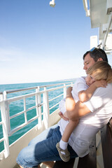 A man and a boy on a white boat in the sea are sitting by the side, father and son are enjoying a sea trip
