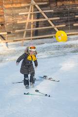 Young skier joyfully navigates snow-covered slope wearing a cozy jacket and bright ski goggles...