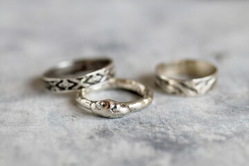 Handcrafted Silver Rings on Textured Surface Unique Jewelry Aesthetic, Close-up View.