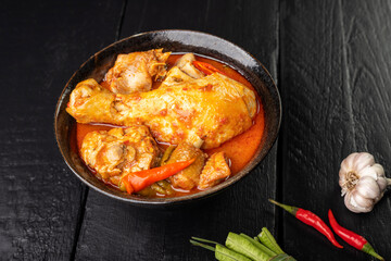 Chicken curry Asian food masala. Traditional cooking healthy food with spices. Arranged on black wooden table background.