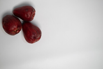 Three Jamaican guavas are arranged on a white surface, forming a simple and natural composition.