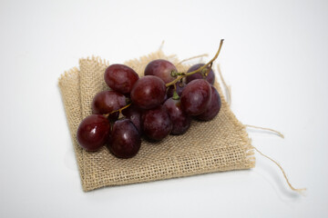 Fresh red grapes placed on a rustic piece of burlap fabric, simple and natural.