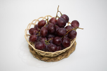 Juicy red grapes beautifully arranged in a rustic wicker basket, ready to eat.