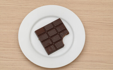 A bitten bar of dark chocolate on a plate