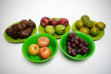A colorful display of tropical fruits arranged neatly on green plates over a white background.