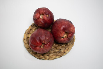 Close up of fresh Jamaican guava fruit with natural skin texture placed on a round rattan tray.