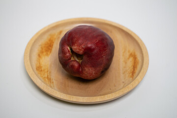 Exotic red water apples are placed on a wooden plate.