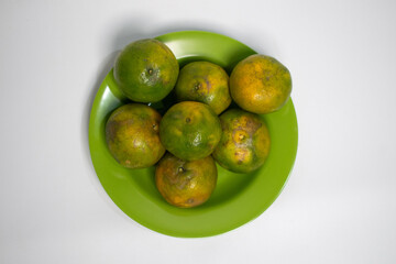 Oranges arranged in a circle on a bright green plate.