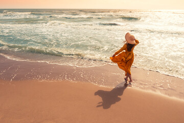Seascape on a sunny day in summer. Woman on the beach, summertime. Young happy woman walks carefree...