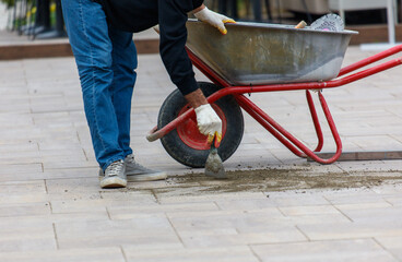 A man is using a wheelbarrow to carry bricks