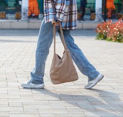 A person is walking down a sidewalk with a brown bag in their hand