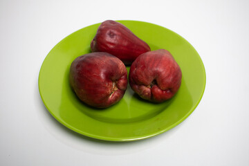 Three ripe water apples on a green plate, ready to eat.