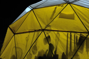 Yellow tent set up by an expedition among the mountains. Camping site. Tourist season. Camp with lights inside in the dark of night.