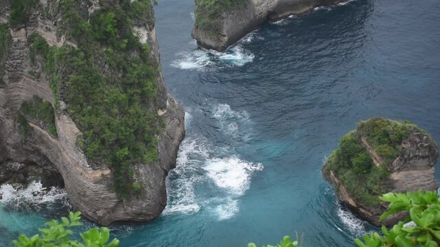 Dramatic cliffside view of Kelingking Beach in Nusa Penida, Bali &ndash; showcasing the raw beauty of turquoise waves crashing against the rugged shoreline.