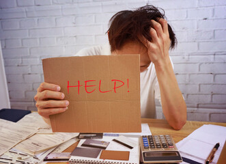 Young asian man headache with a lots of Invoice as concerned  looking at many credit cards scared...
