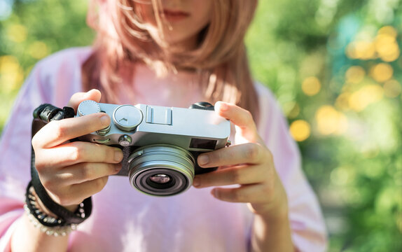 Young photographer adjusting settings on her camera in a park