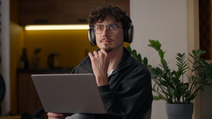 Thoughtful Caucasian guy hipster using laptop computer buying goods online at home male freelancer...
