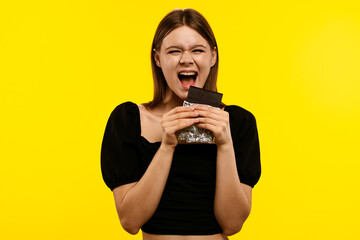 Young Woman Joyfully Eating a Bar of Dark Chocolate