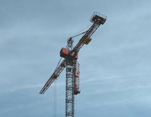steel construction crane set against a clear blue sky. The crane is elevated and ready for lifting