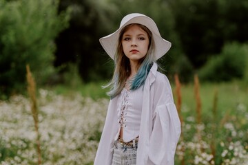 A teenage girl with colorful hair and a stylish hat explores a sunlit daisy field, radiating...