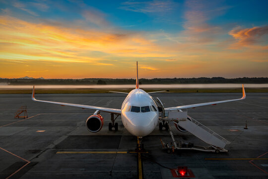 Commercial airliner parked on the tarmac at sunrise at the Milan Malpensa International Airport.