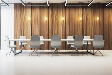 Modern empty boardroom with minimalist design, wooden wall panels, and stylish lighting over...
