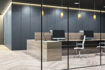 Modern dark grey office interior featuring wooden desks, glass partitions, pendant lamps, and...