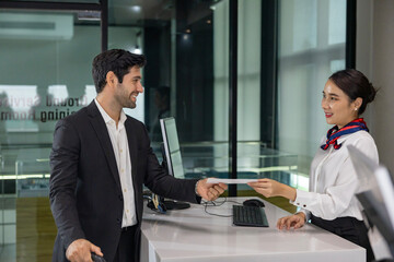 Caucasian businessman passenger is receiving boarding pass from the airline ground crew at check in counter at departure terminal into the airplane for final inspection before boarding the plane