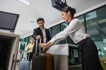 Caucasian businessman passenger is checking in big baggage bag to airline ground crew at departure...