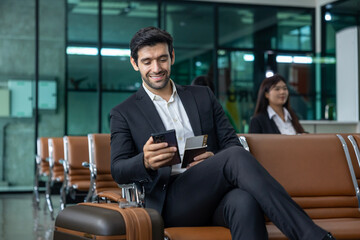 Caucasian businessman is using smart mobile phone while waiting in airline business departure lounge waiting for boarding airplane usage