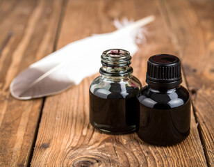 Old ink bottles and a white feather pen on rustic wooden table, representing classic writing tools and vintage creativity.