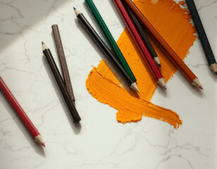Collection of colored pencils and oil paint on a white marble surface for art and drawing projects