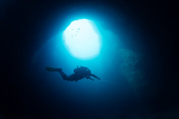 diver exploring inside an underwater cave, concept of scuba diving and underwater adventure, copy space for text