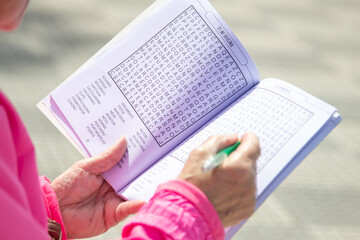 senior woman doing crossword puzzles relaxing sitting on the street