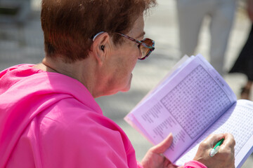 senior woman doing crossword puzzles relaxing sitting on the street