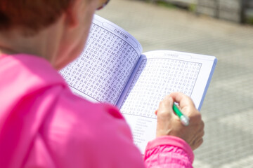 senior woman doing crossword puzzles relaxing sitting on the street