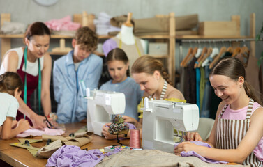 Sewing lesson - a group of teenage children learn to sew on a sewing machine and cut fabric