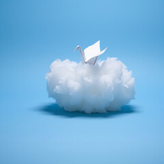 A delicate paper origami swan perched on a fluffy white cotton cloud against a vibrant blue background, creating a whimsical and surreal scene that combines nature and art.