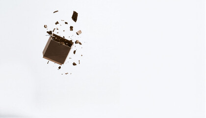 A broken chocolate bar with splattered pieces on a plain white background, highlighting the texture and rich brown color of the chocolate