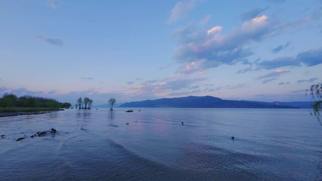 Gentle waves on Erhai Lake with small ducks floating under the golden hues of dusk. Ideal for cinematic travel scenes or peaceful storytelling.