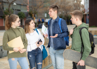 Teenage students spending time together after lessons, talking and having fun outdoors