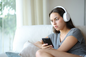 Angry woman listening audio in a house